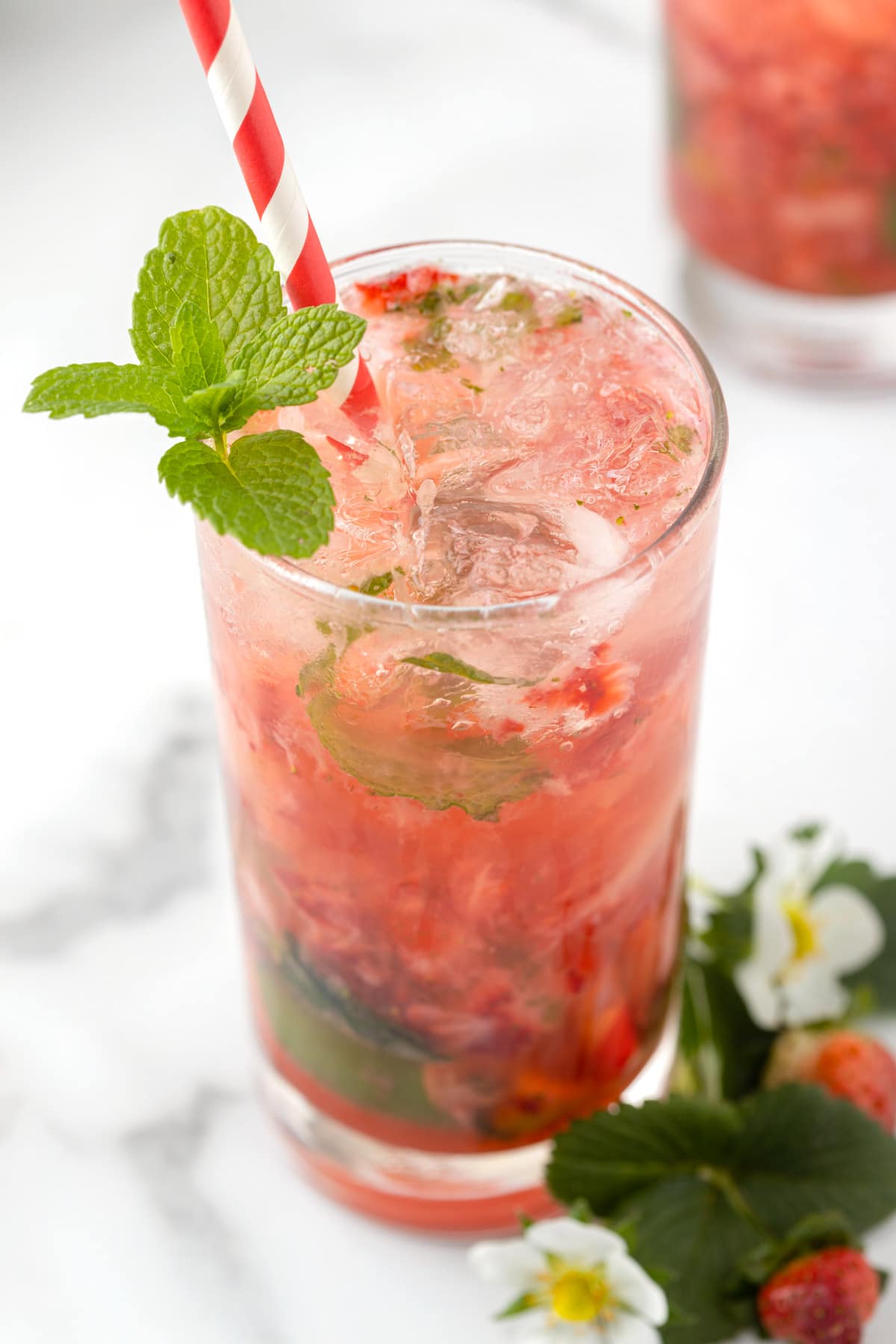 closeup of a strawberry mojito in a highball glass with a sprig of mint