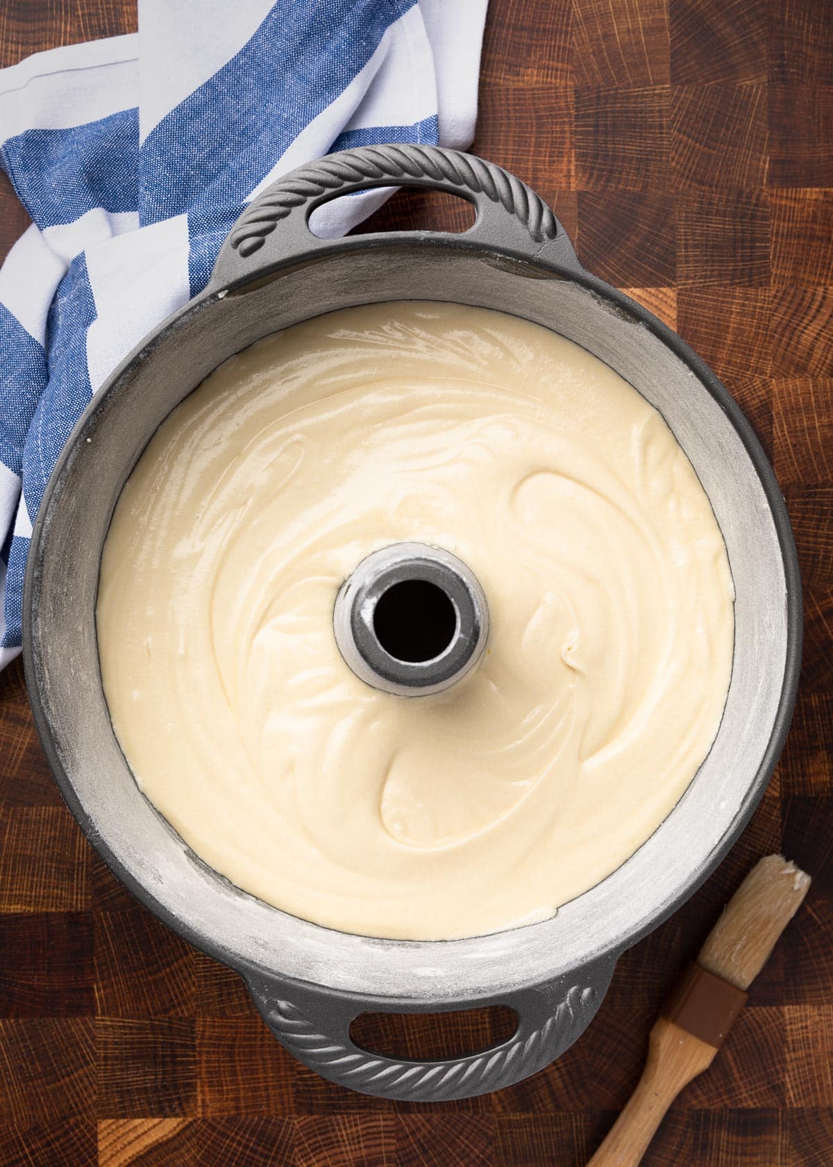 overhead photo of pound cake batter in a tube pan with a blue and white striped napkin