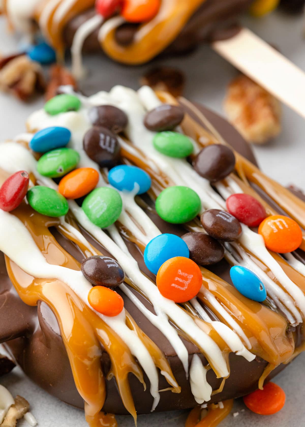 close up of chocolate covered caramel apple slices decorated with mini M&M candies