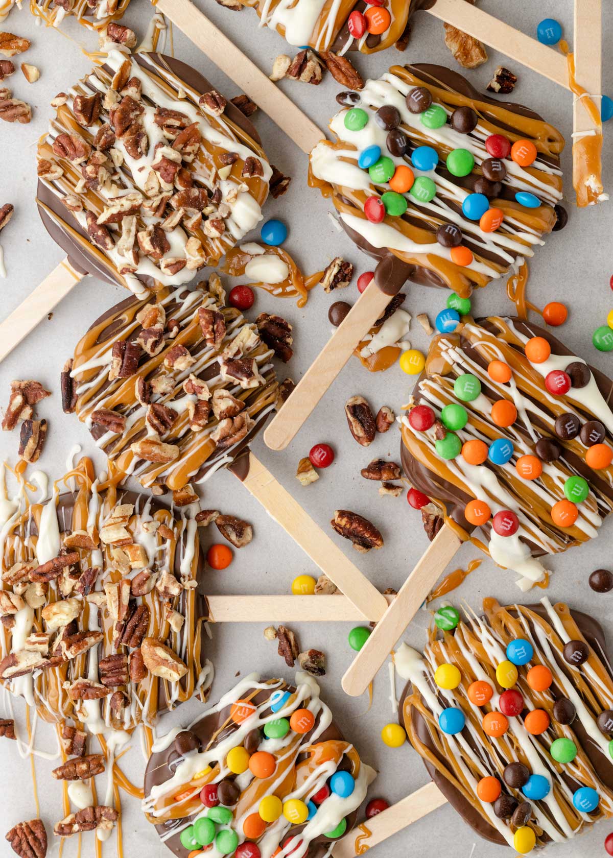 caramel apple slices on a parchment lined baking sheet with pecans and M&M's