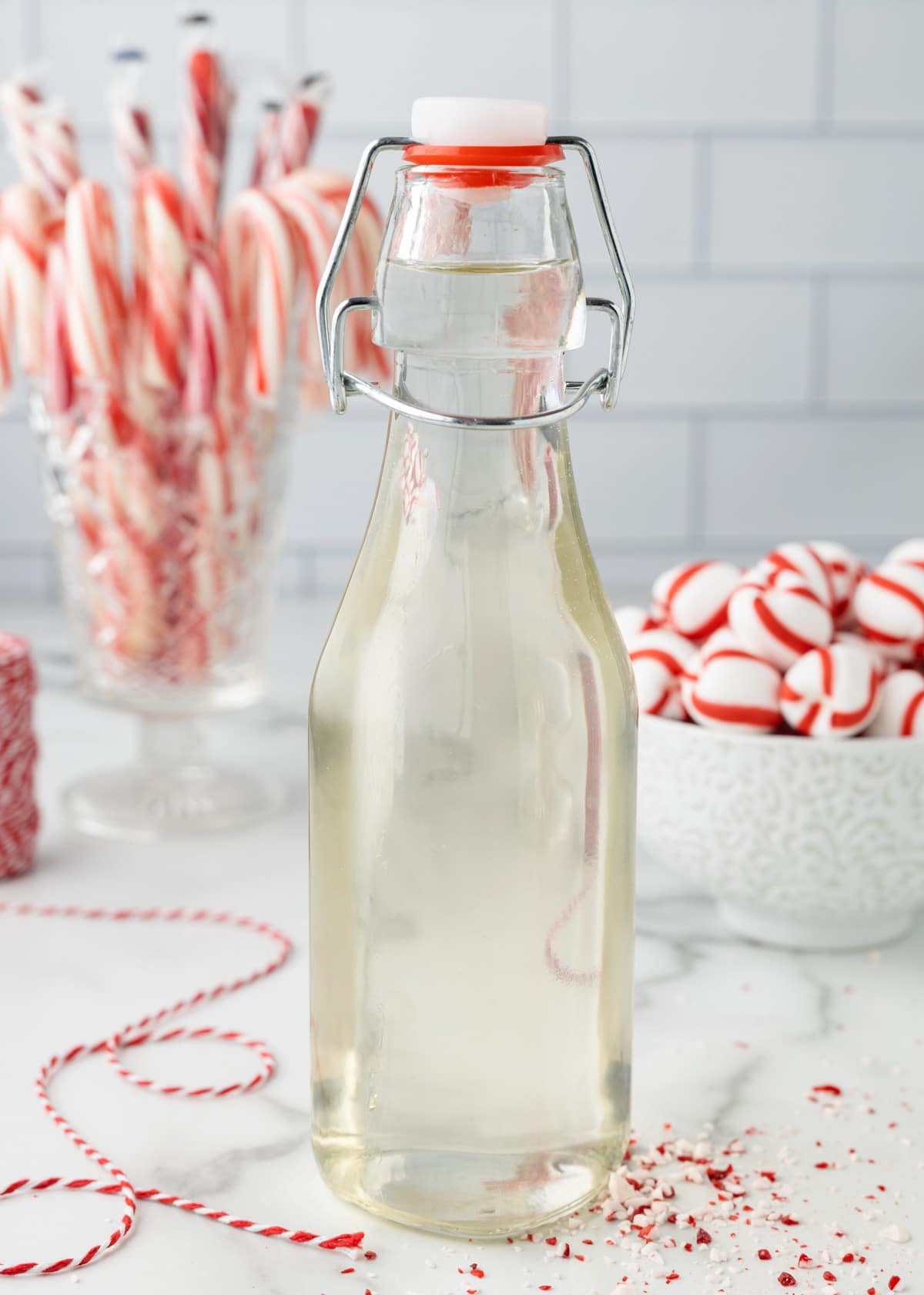 peppermint syrup in a glass bottle surrounded by candy canes and peppermint candies