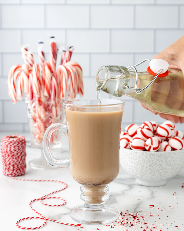 peppermint syrup being poured into a coffee drink in a glass mug