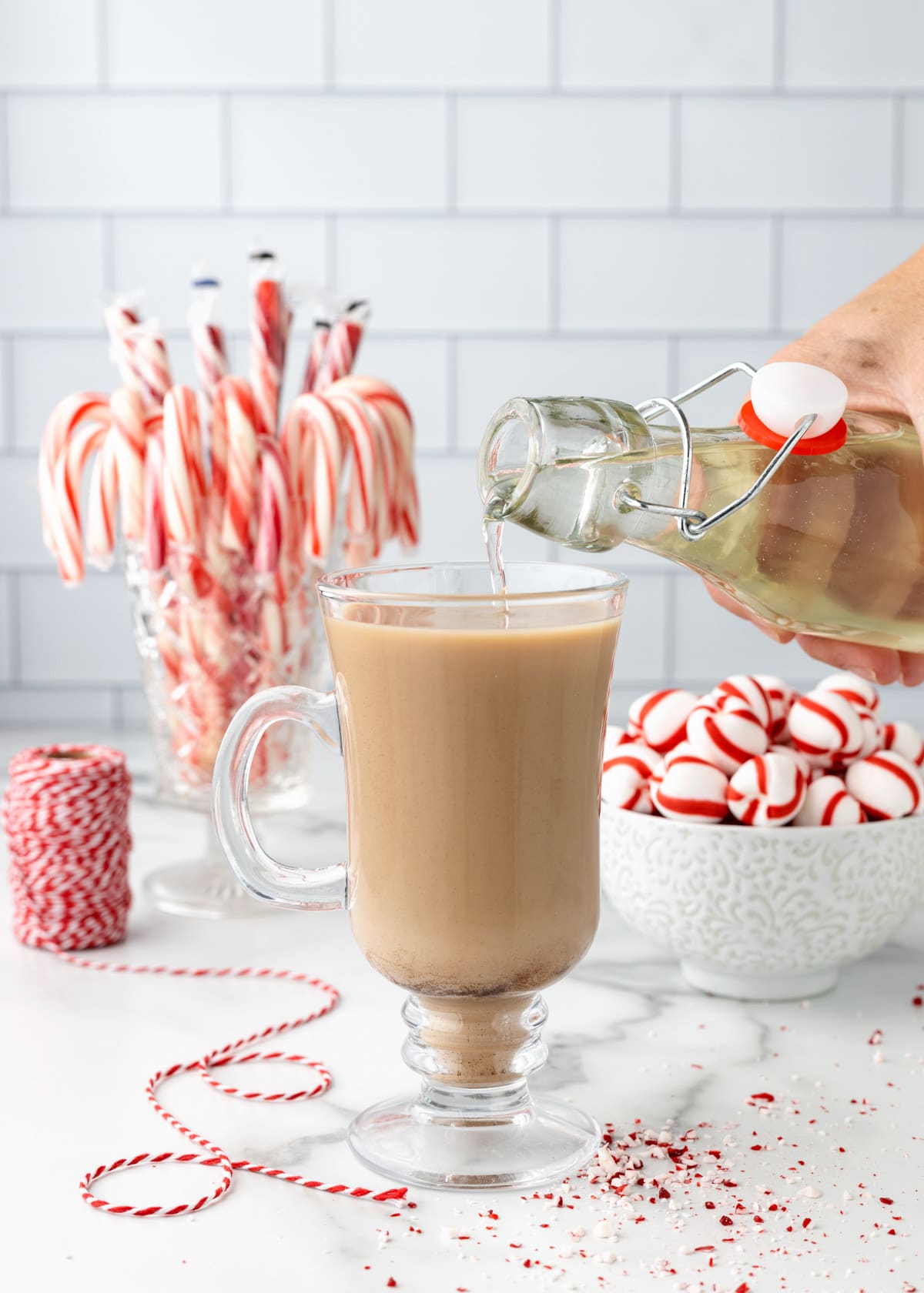 peppermint syrup being poured into a coffee drink in a glass mug