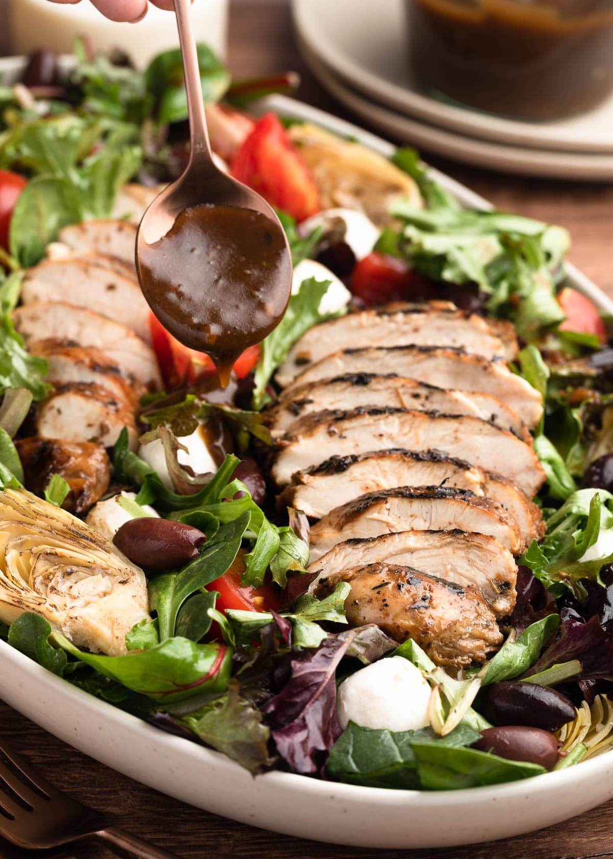 balsamic vinaigrette being drizzled over chicken salad with a bronze spoon