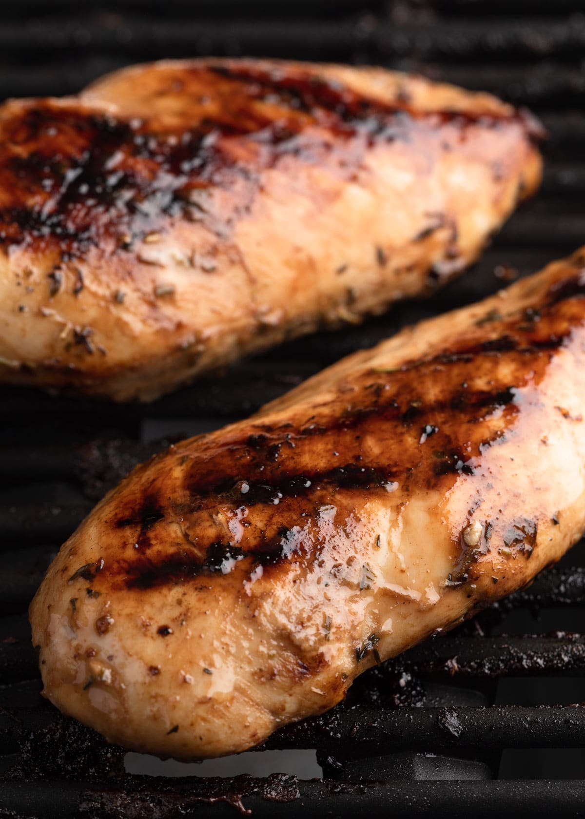 two cooked balsamic marinated chicken breasts on grill grates