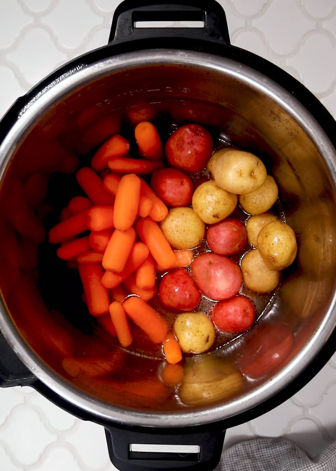 uncooked baby carrots and creamer potatoes in an instant pot