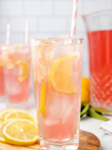 two glasses of pink lemonade with lemon slices and pink striped paper straws