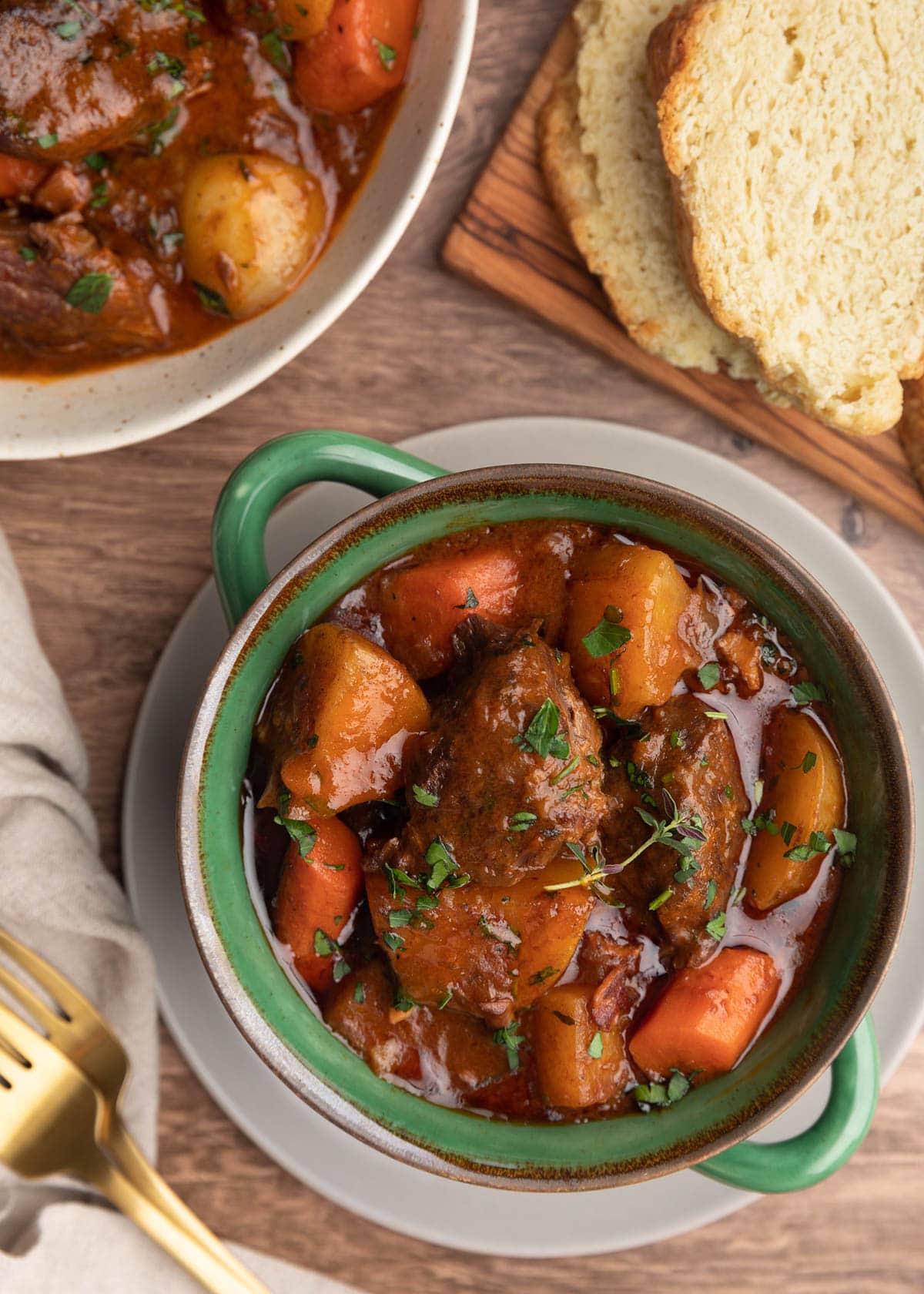 overhead photo of Guinness beef stew with root vegetables in a green double handled crock