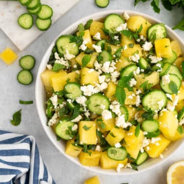 watermelon feta and cucumber salad in a white bowl with a blue and white striped napkin