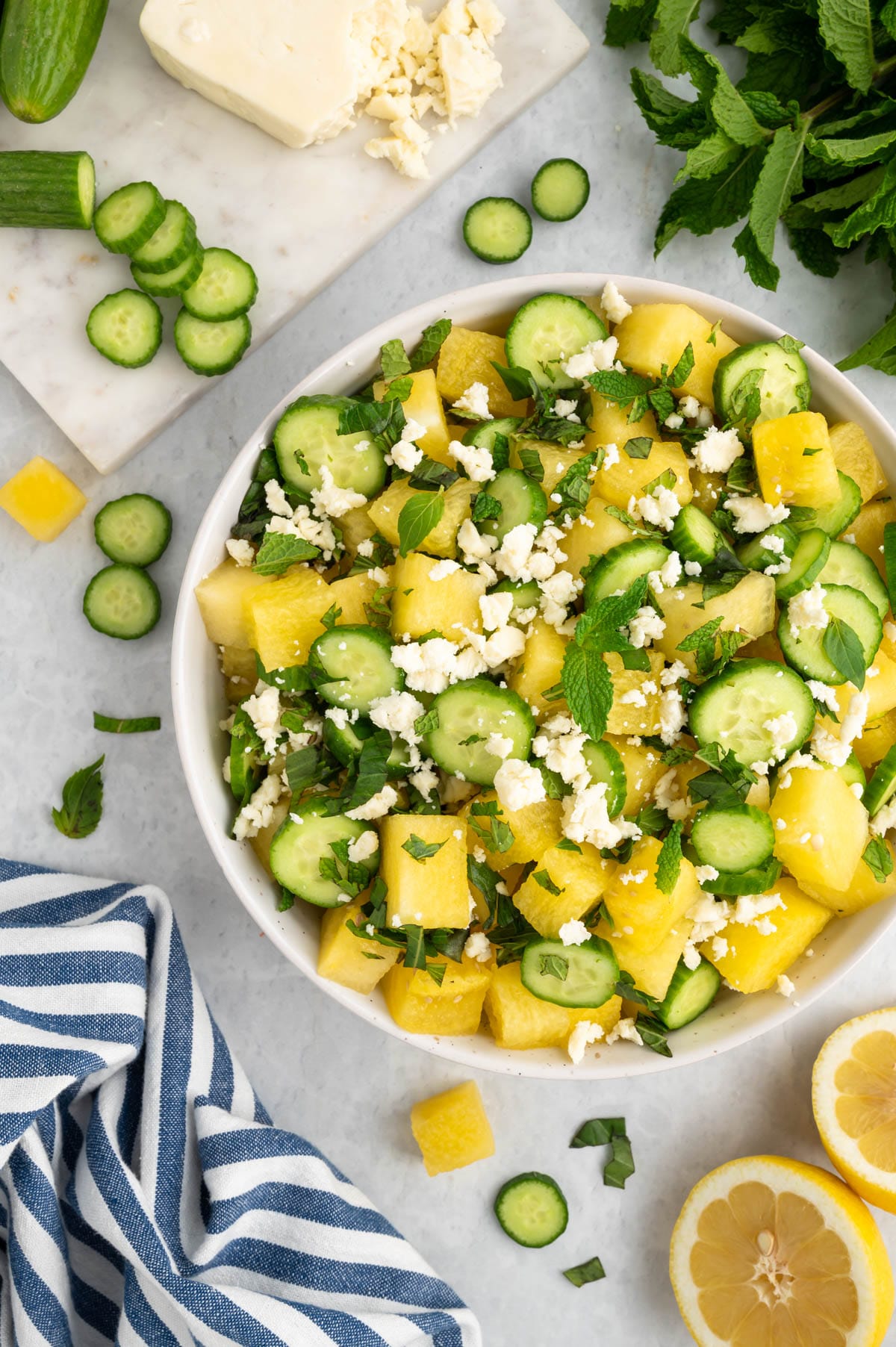 watermelon feta and cucumber salad in a white bowl with a blue and white striped napkin