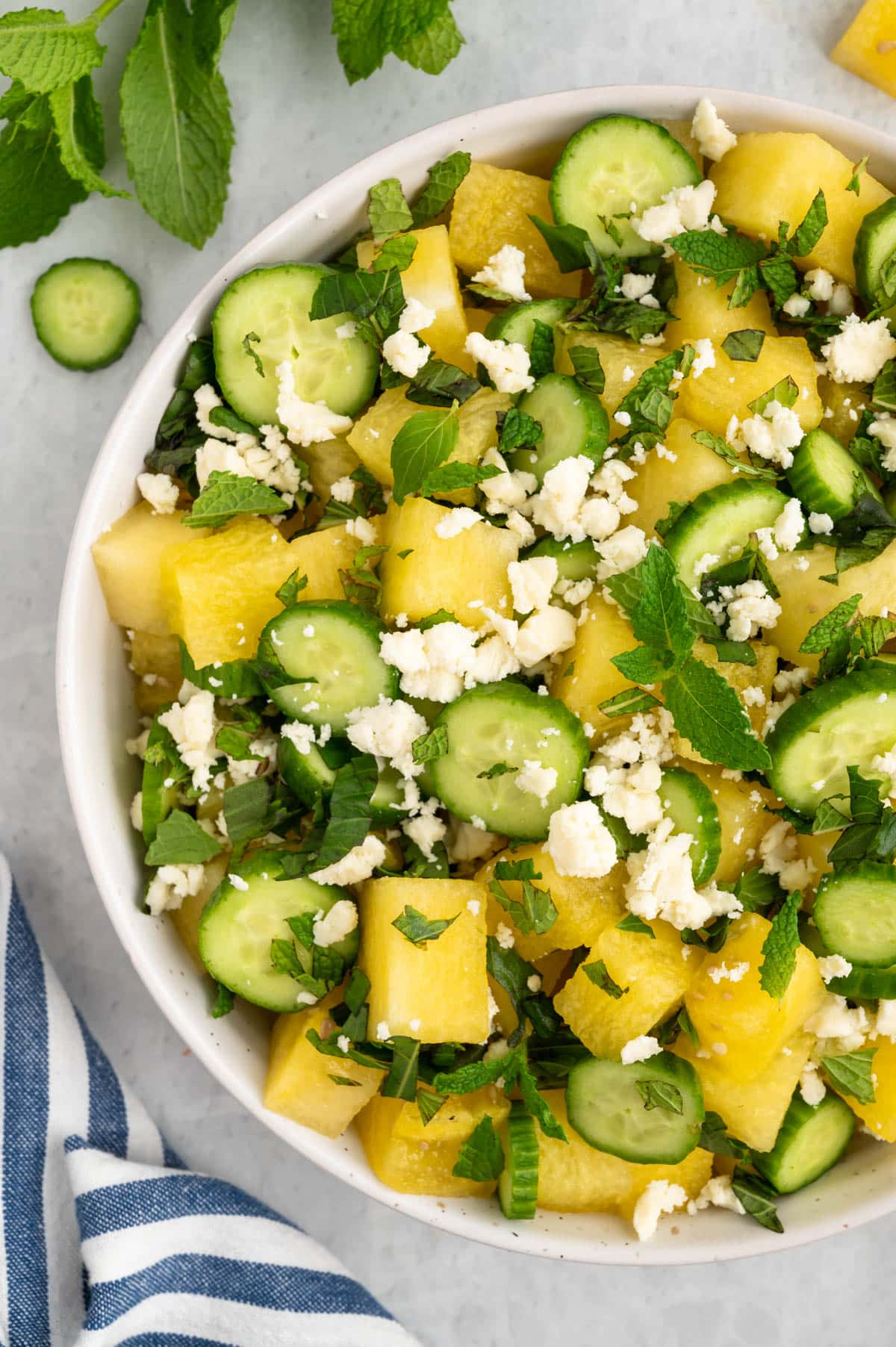 overhead closeup of yellow watermelon and feta salad in a white bowl