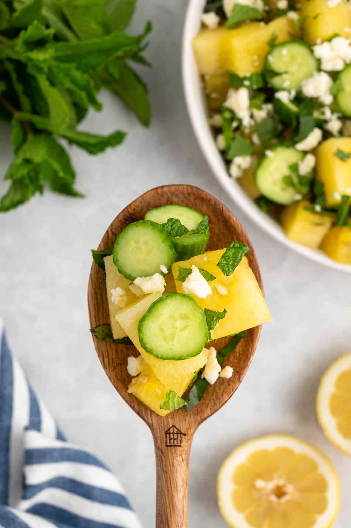 overhead photo of watermelon salad on a wooden spoon