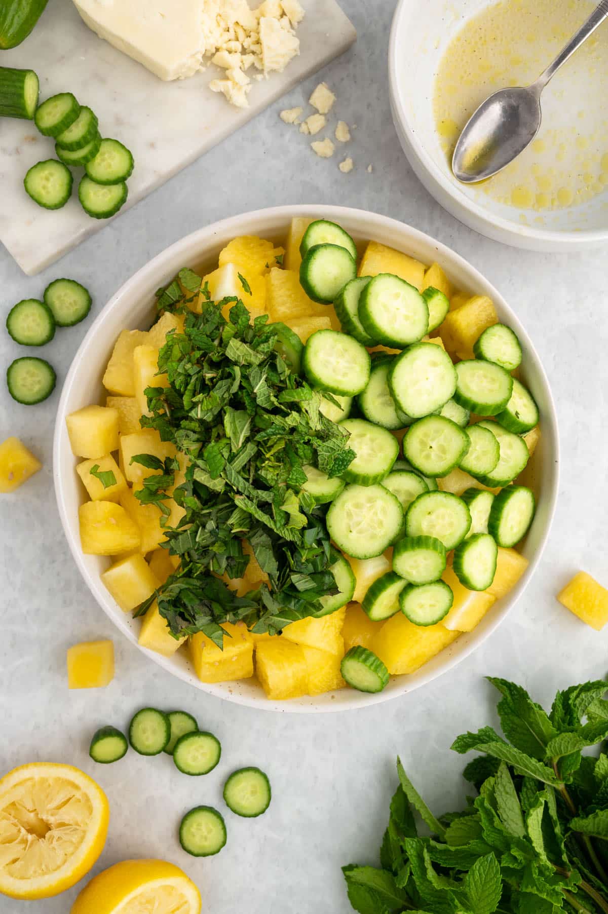 overhead photo of watermelon and cucumber salad being assembled in a white bowl