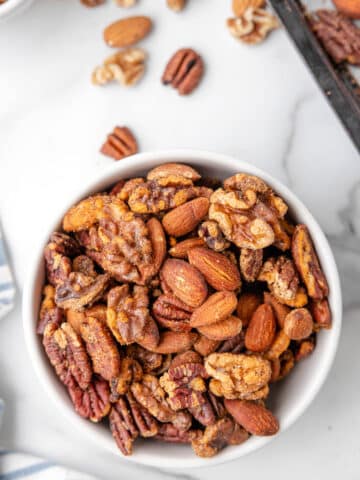 cajun spicy mixed nuts in a white bowl on a marble board