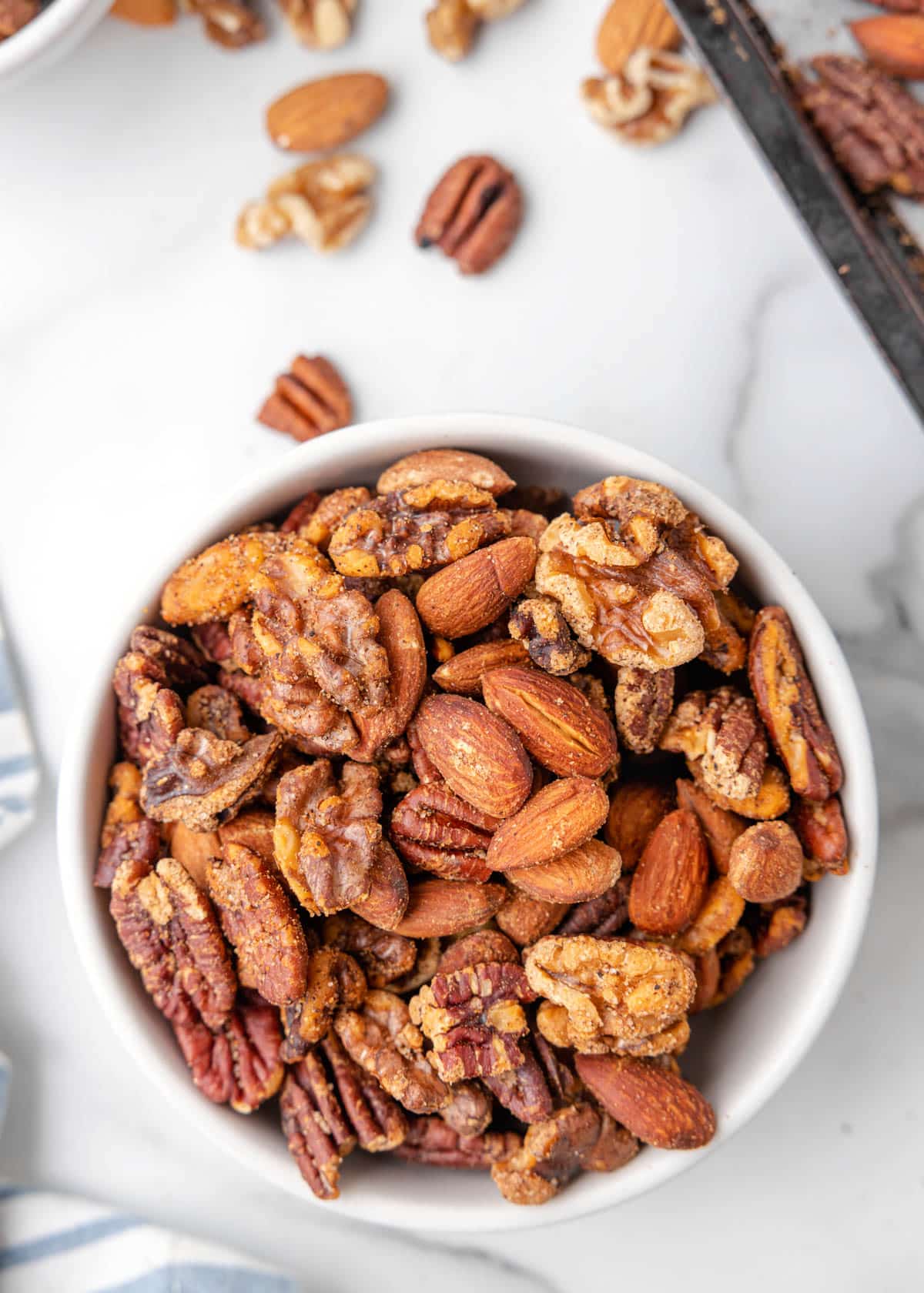 cajun spicy mixed nuts in a white bowl on a marble board