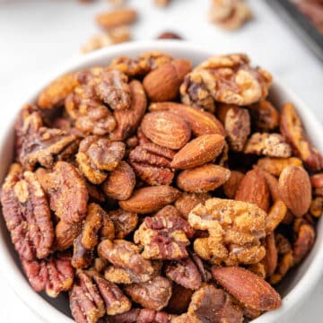 cajun spiced nut mix in a white bowl on a marble board