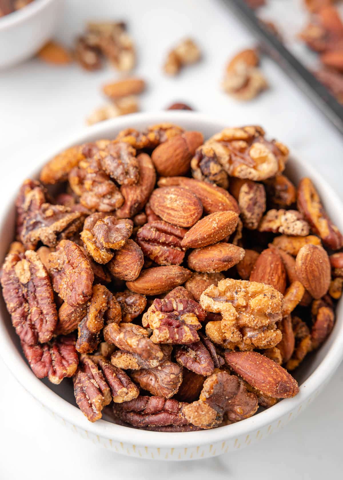 cajun spiced nut mix in a white bowl on a marble board