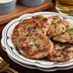corned beef and potato cakes on a white and blue scalloped dish