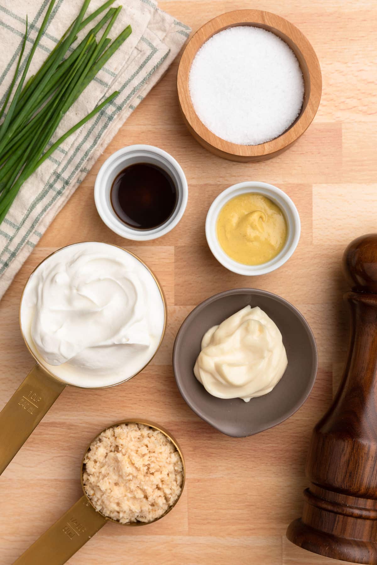 overhead photo of ingredients needed to make creamy horseradish sauce in bowls on a butcher block board