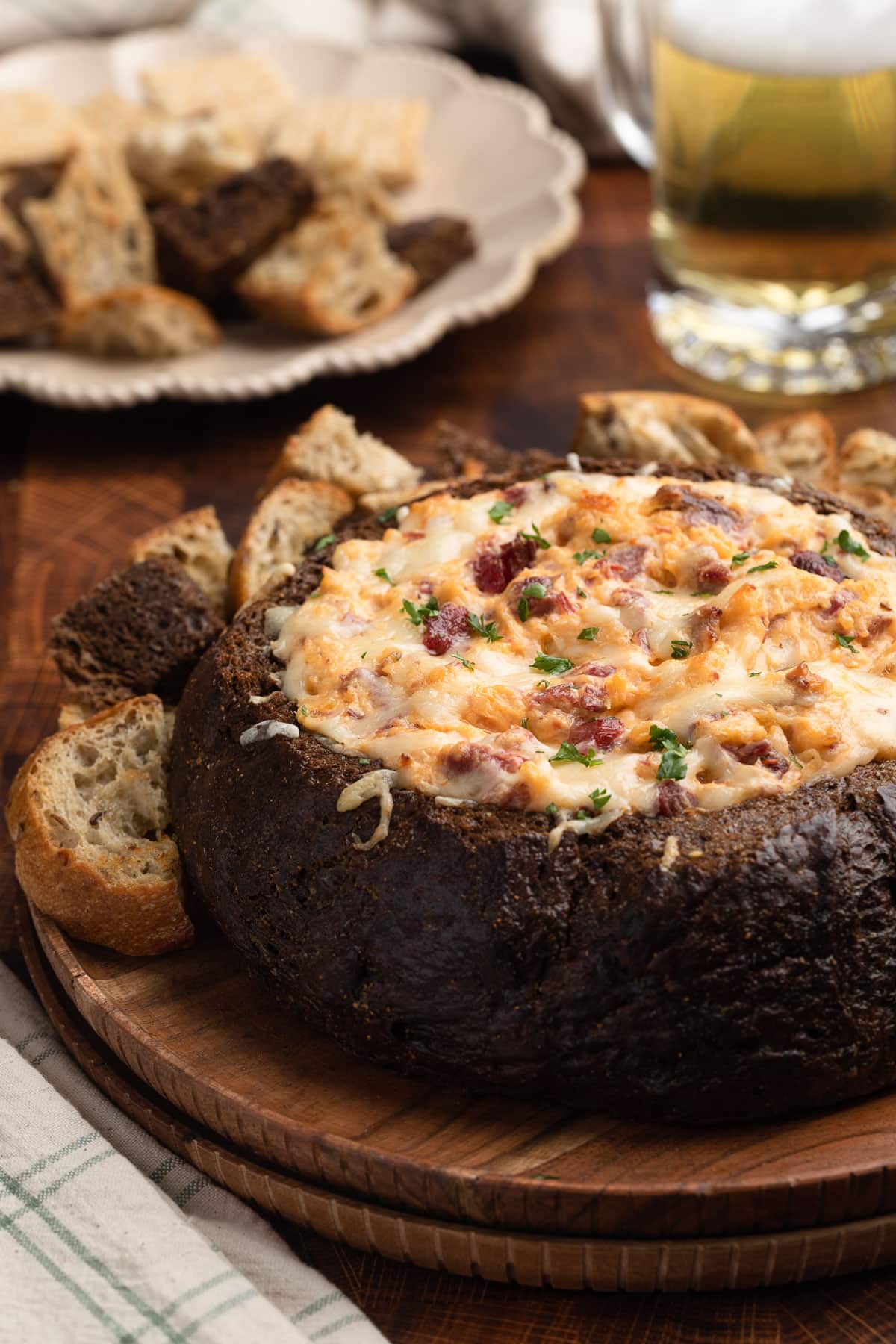 baked reuben dip in a pumpernickel bread bowl on a wood platter with chunks of toasted bread