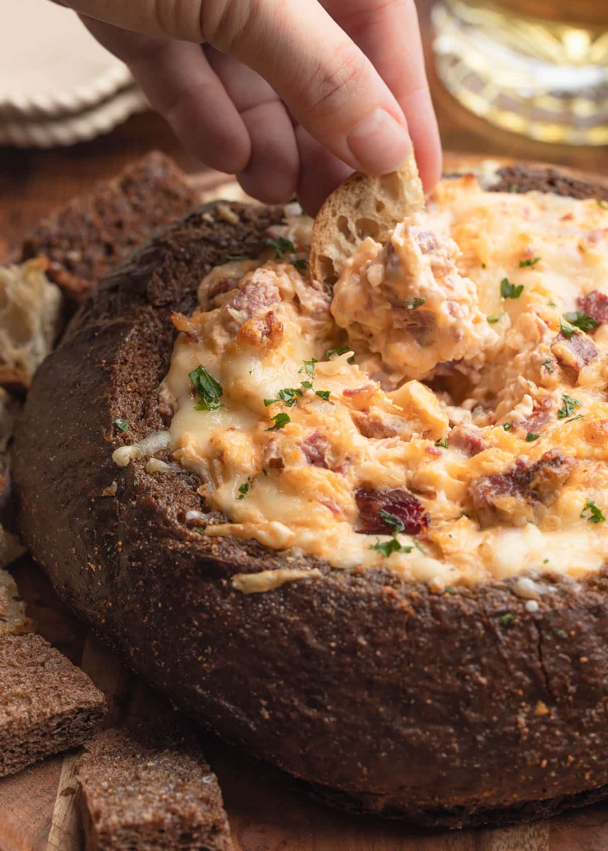 reuben dip in a bread bowl dipped with a rye bread dipper