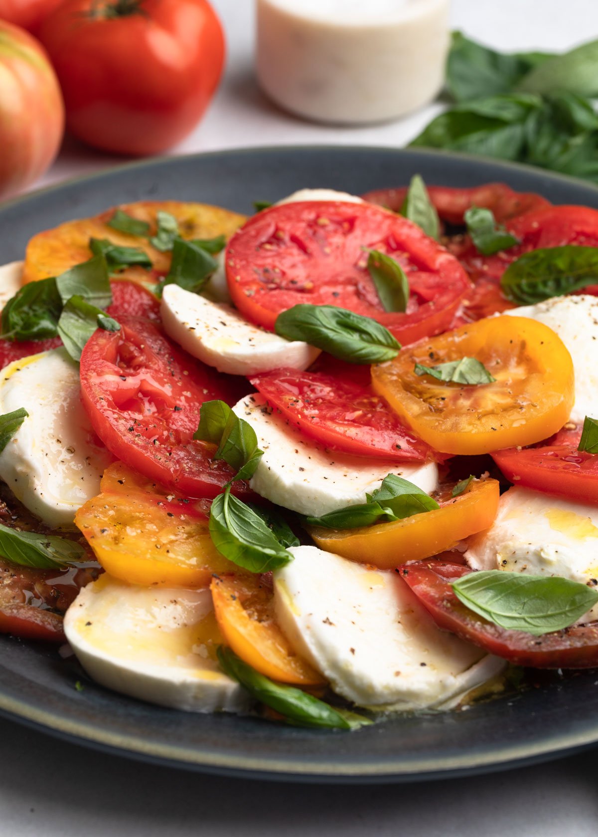 closeup of caprese salad (sliced mozzarella, tomato, and basil) on a round gray platter