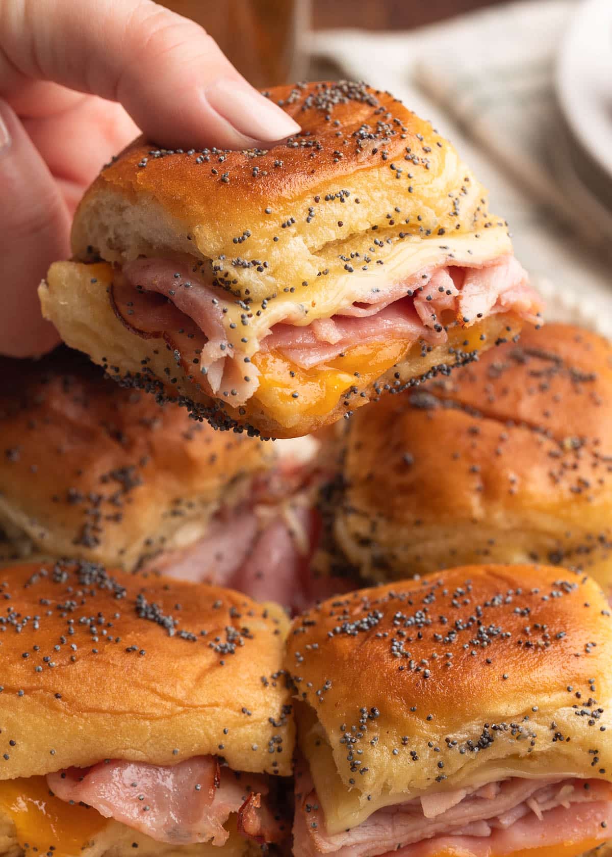 closeup of a baked ham and cheese slider being picked up from a platter