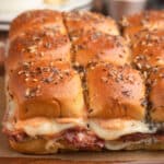 slab of Reuben sliders on Hawaiian buns on a wooden serving board