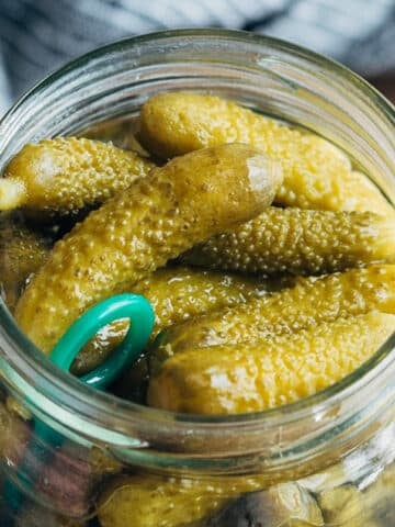 closeup of French cornichon pickles in a glass jar