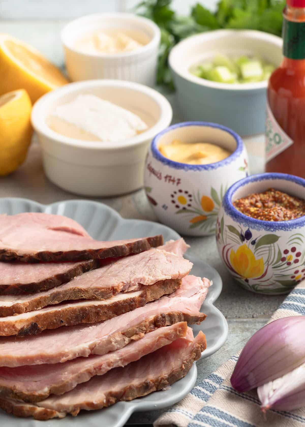 ingredients for deviled ham spread on plates and in bowls on a tile board