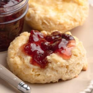 closeup of irish scone spread with butter and strawberry jam
