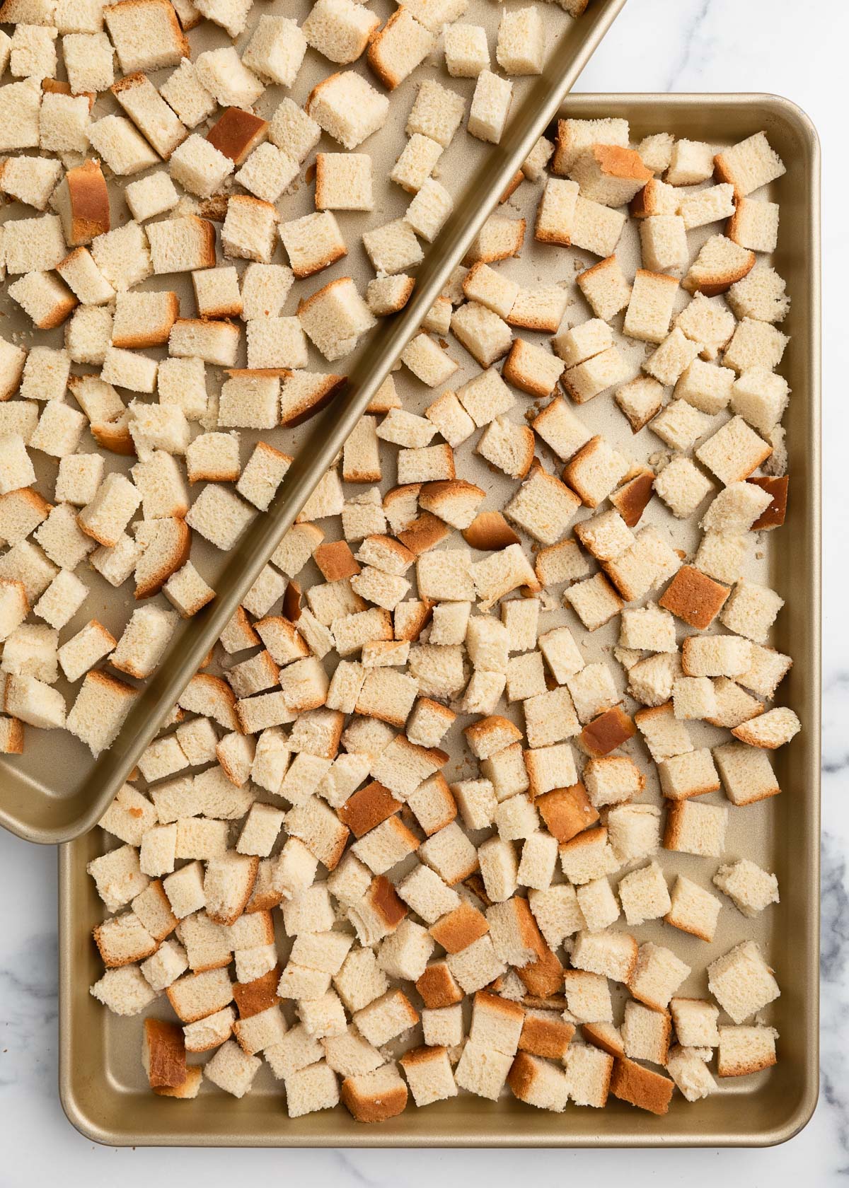 country white bread cubes on two overlapping half sheet pans