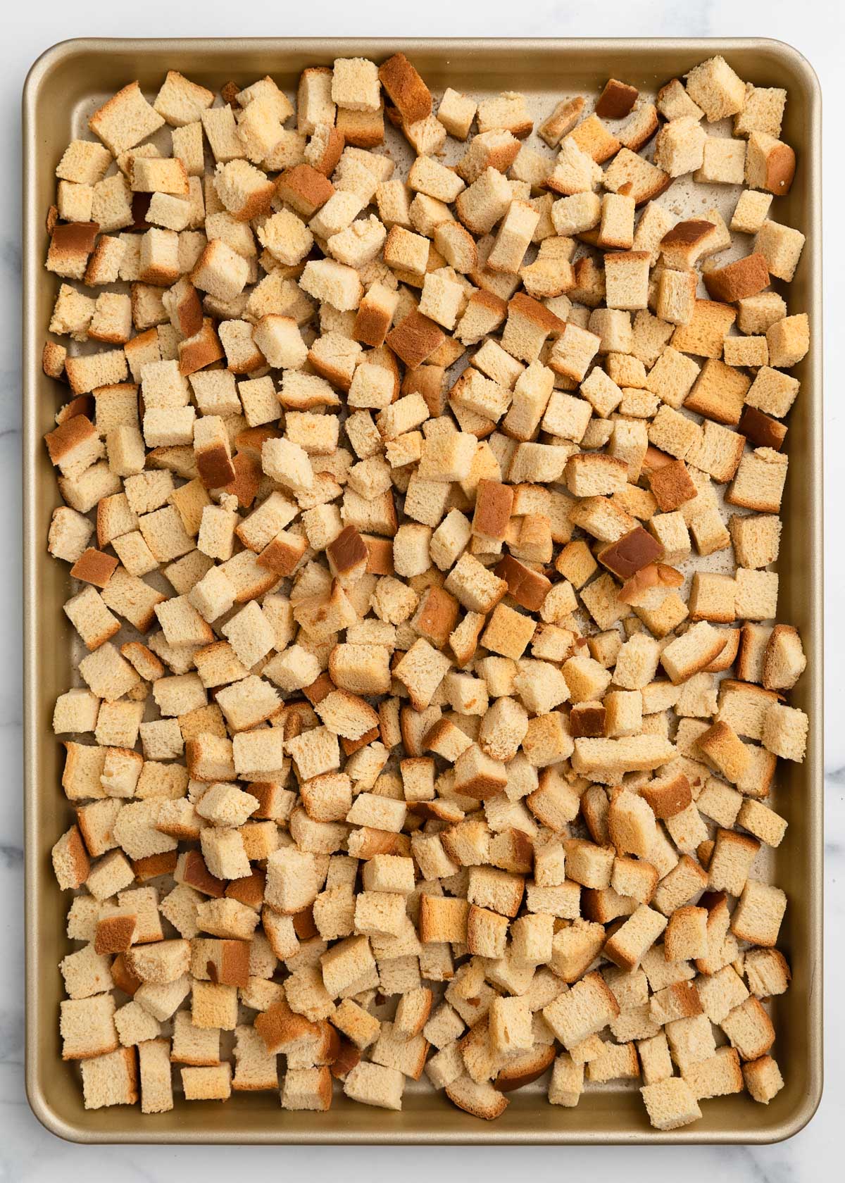 baked country white bread croutons on a rimmed half sheet pan