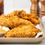 breaded chicken tenders on a parchment lined baking sheet