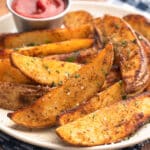 air fried seasoned potato wedges on an ivory speckled plate with a condiment cup of ketchup
