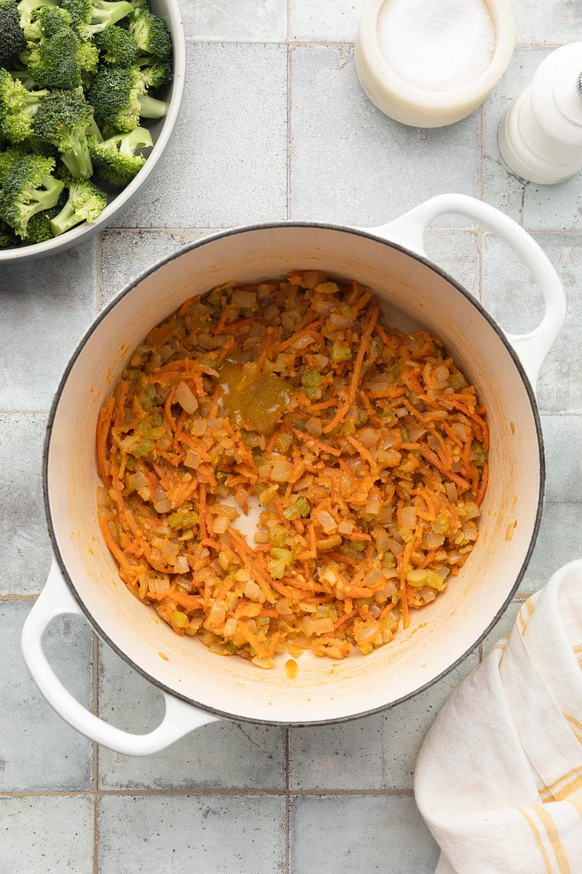 sauteed mirepoix coated with flour with a dollop of roasted chicken base in a white enameled cast iron dutch oven