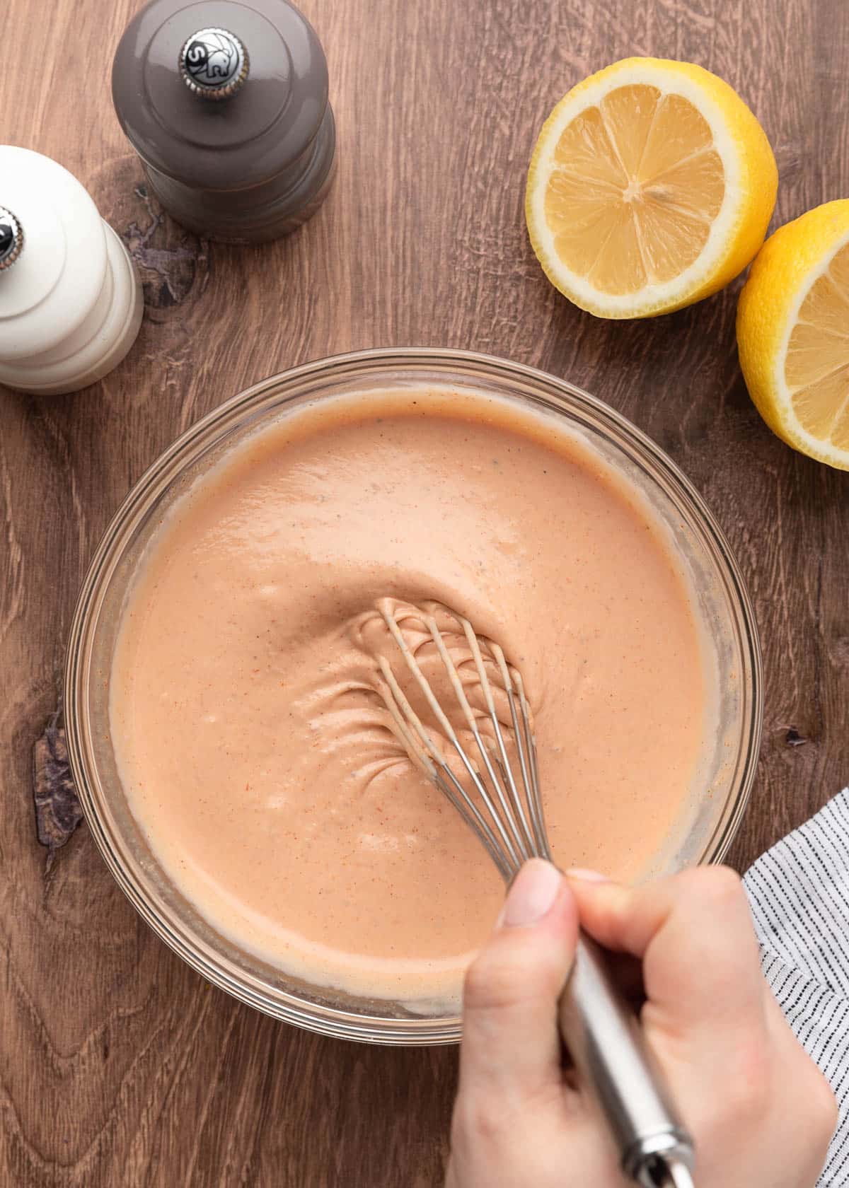 fully mixed comeback sauce being stirred with a whisk in a glass bowl on a wooden board
