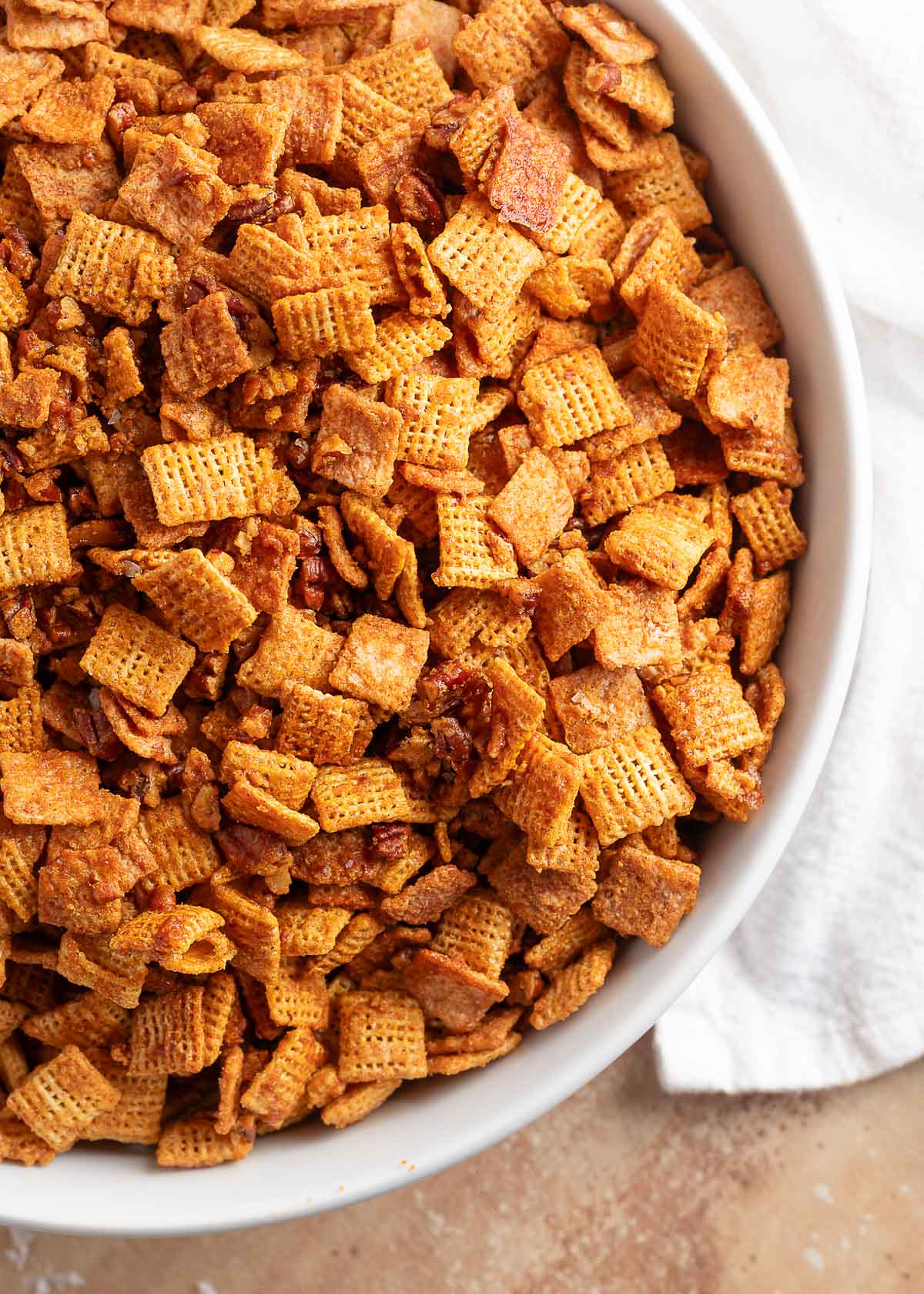 praline crunch snack mix made with cinnamon toast crunch, chex cereal, and pecans in a white bowl