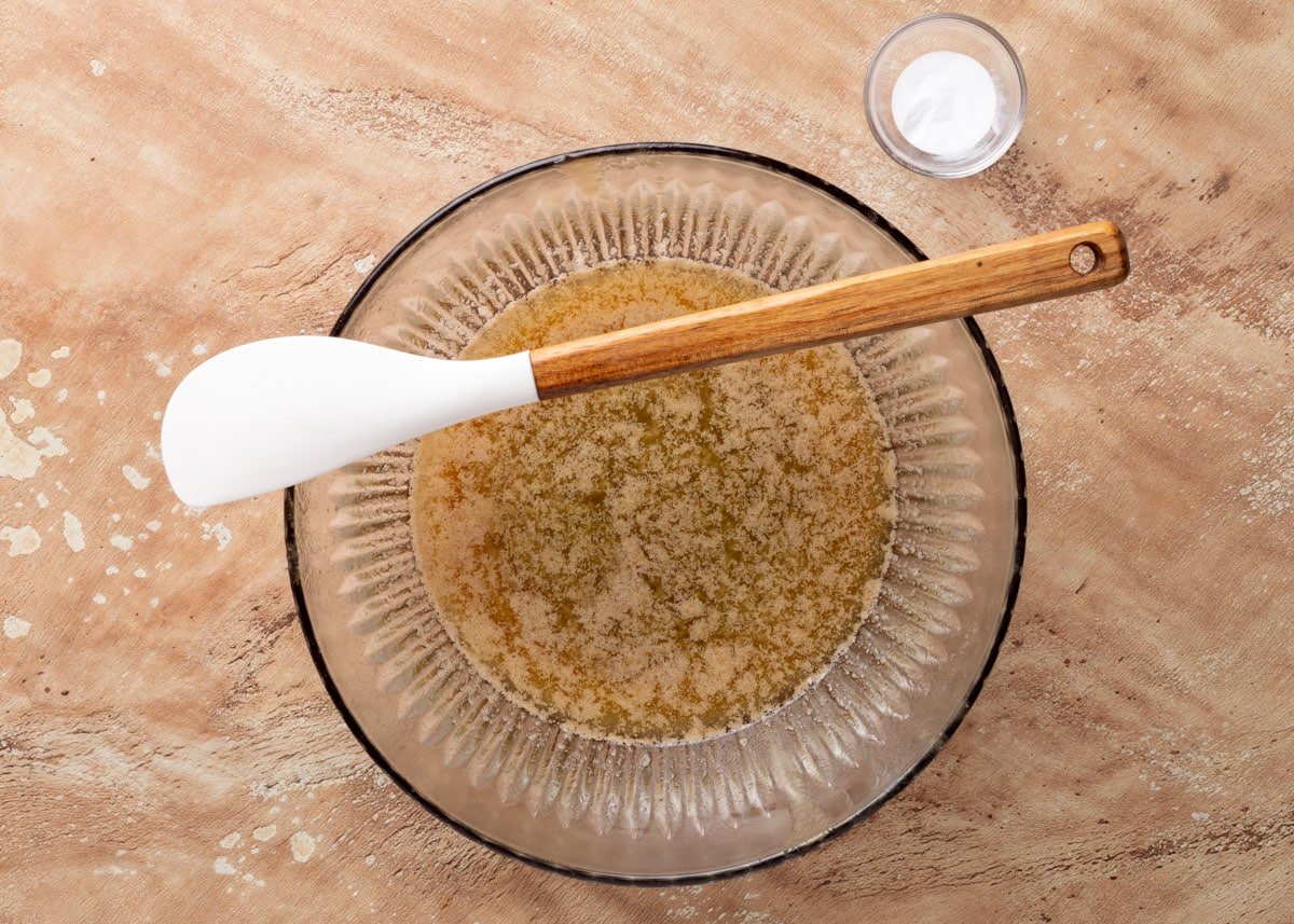 melted butter, brown sugar, and corn syrup in a glass bowl with a white rubber spatula