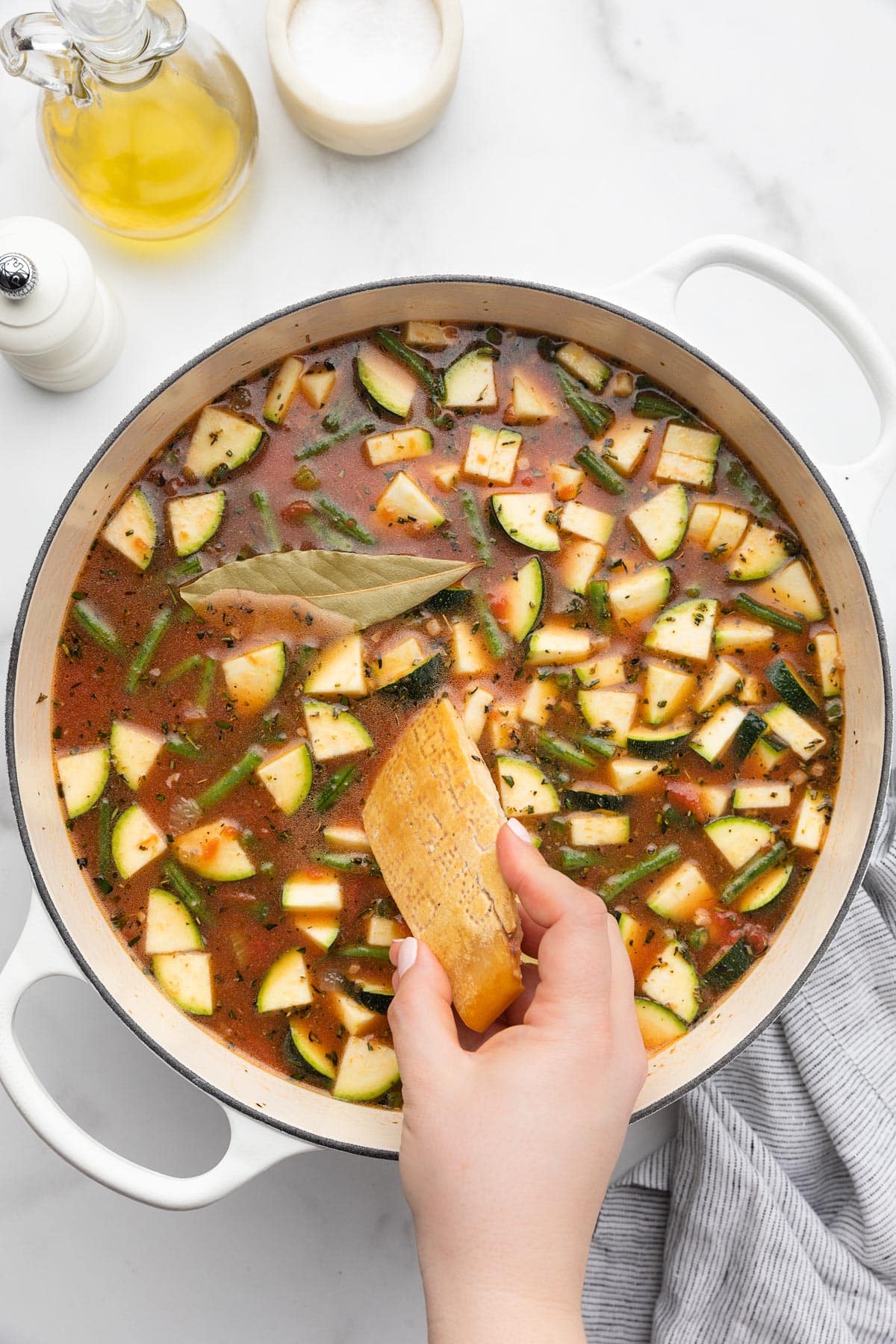adding a parmigiano reggiano rind to an uncooked pot of minestrone soup