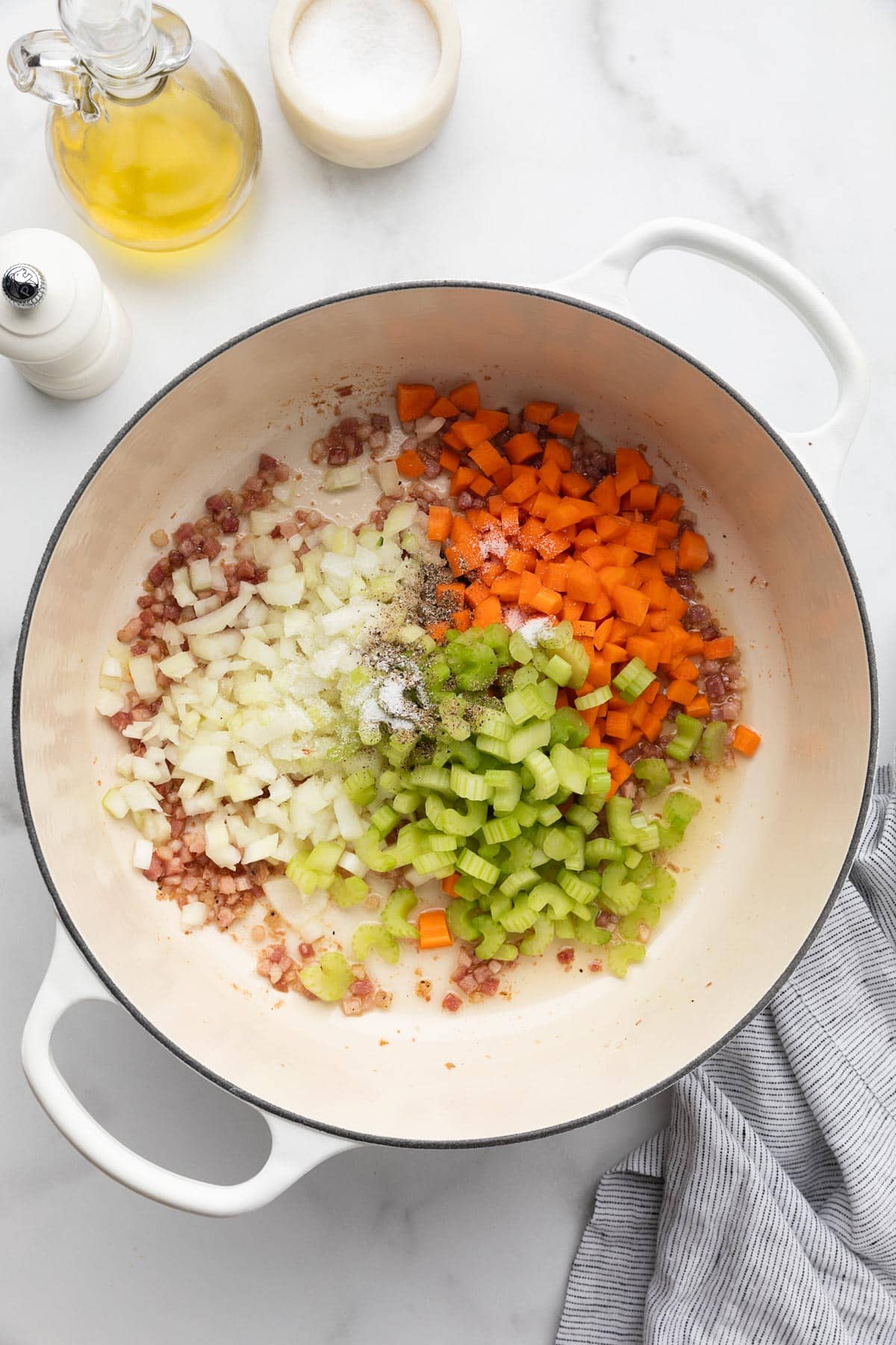 diced celery, carrots, and onions in a white enameled cast iron Dutch oven with fried diced pancetta