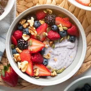 blueberry blended cottage cheese in a white bowl with mixed pepitas, pepitas, and walnuts