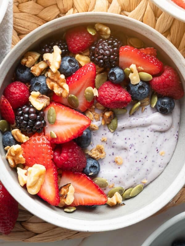 blueberry blended cottage cheese in a white bowl with mixed pepitas, pepitas, and walnuts