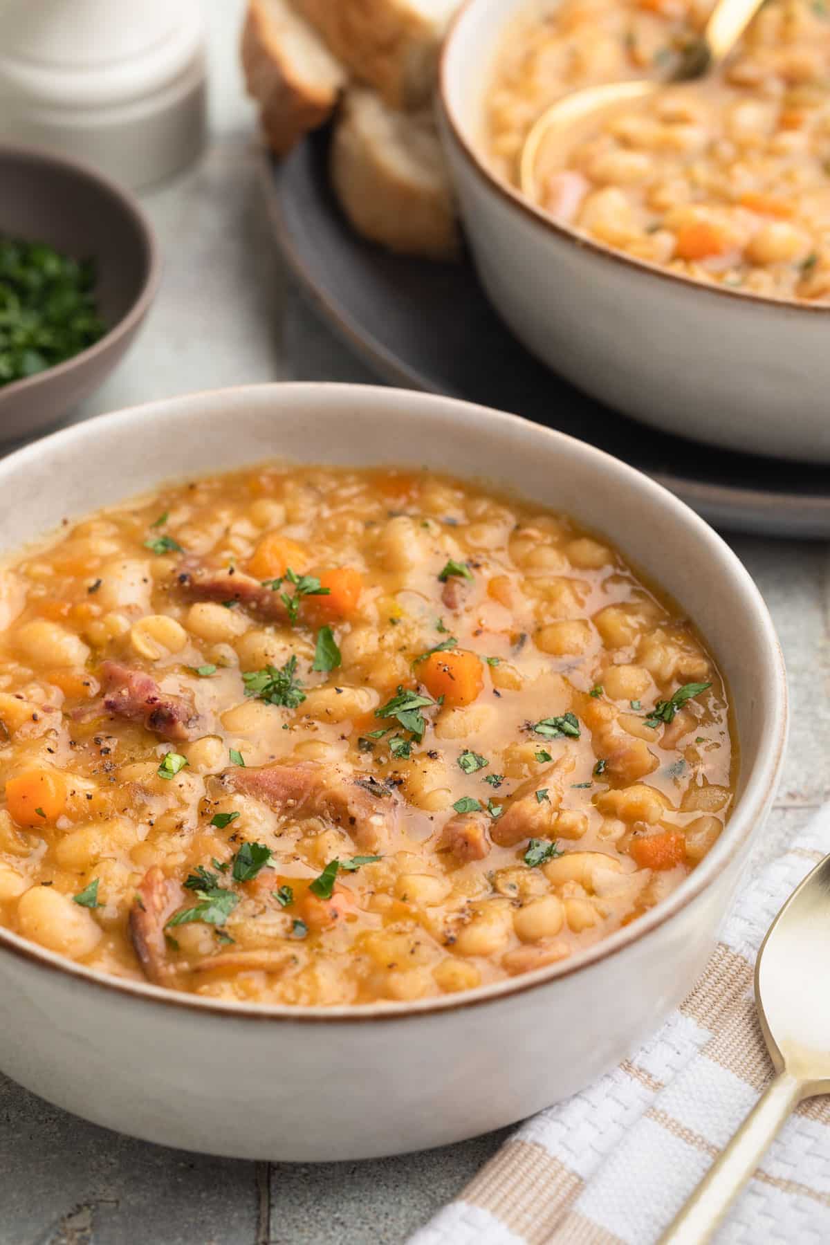 ham and bean soup in an ivory ceramic bowl garnished with fresh parsley