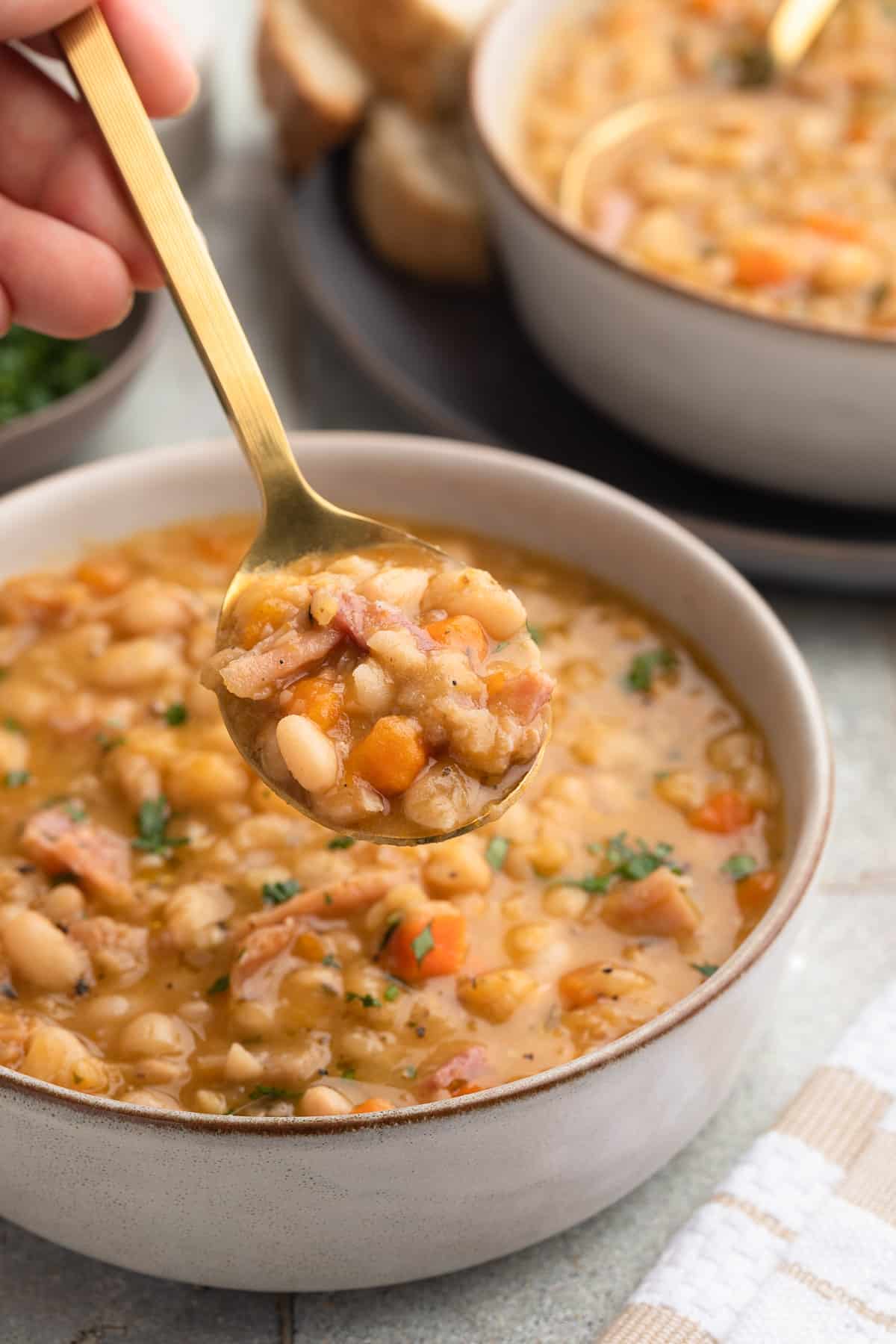 spoonful of ham and bean soup held over a bowl of the soup