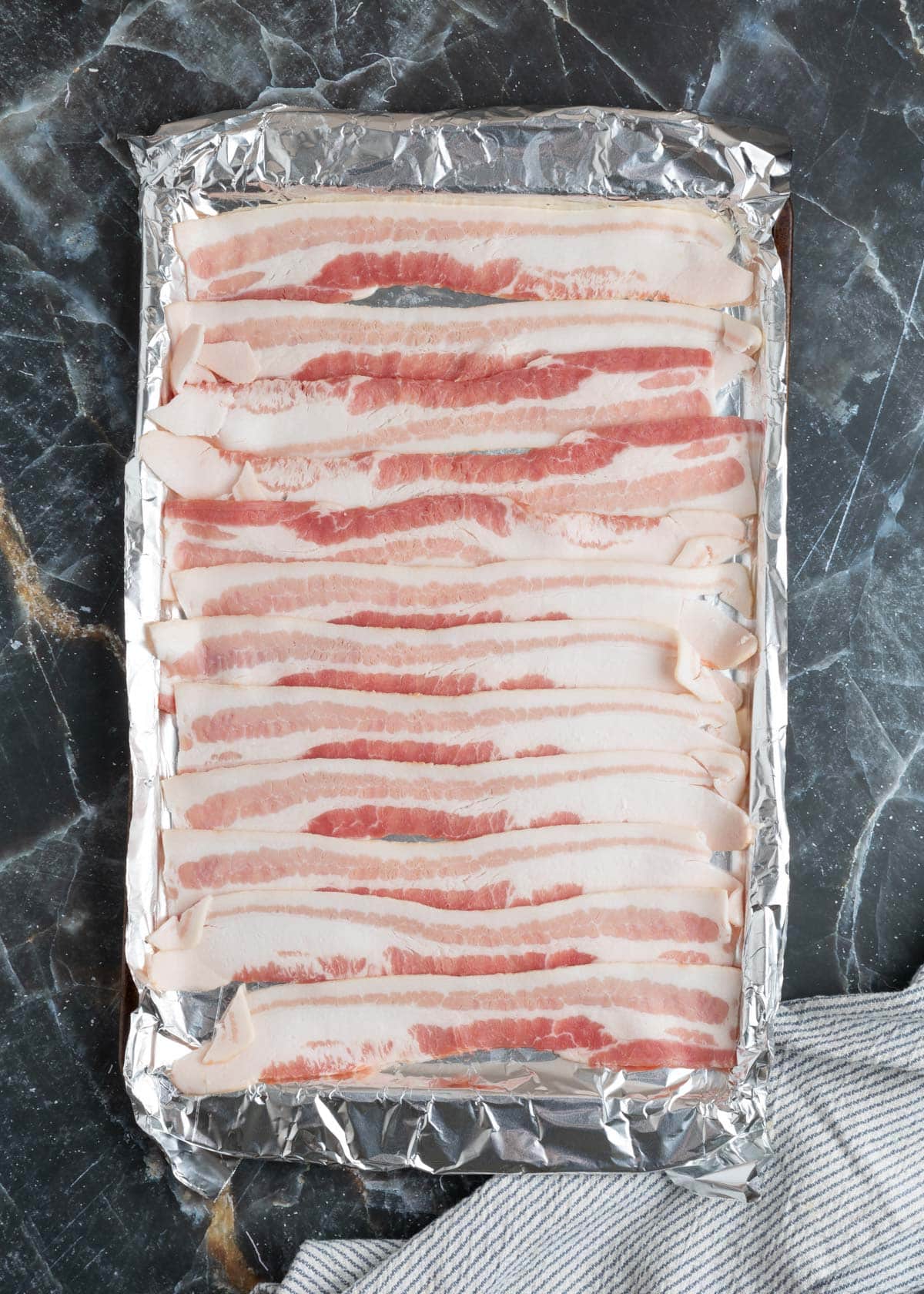 raw bacon on a foil-lined baking sheet