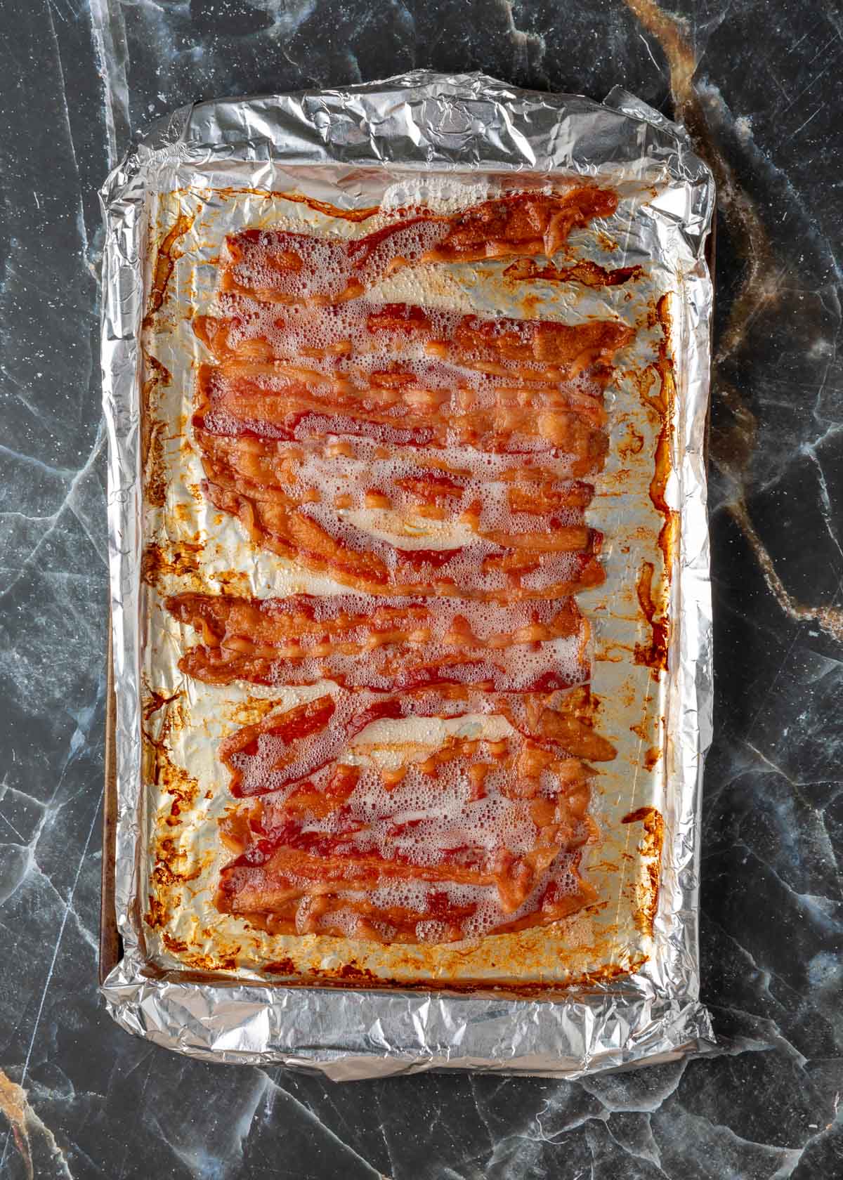 crisp-cooked bacon on a foil-lined baking sheet