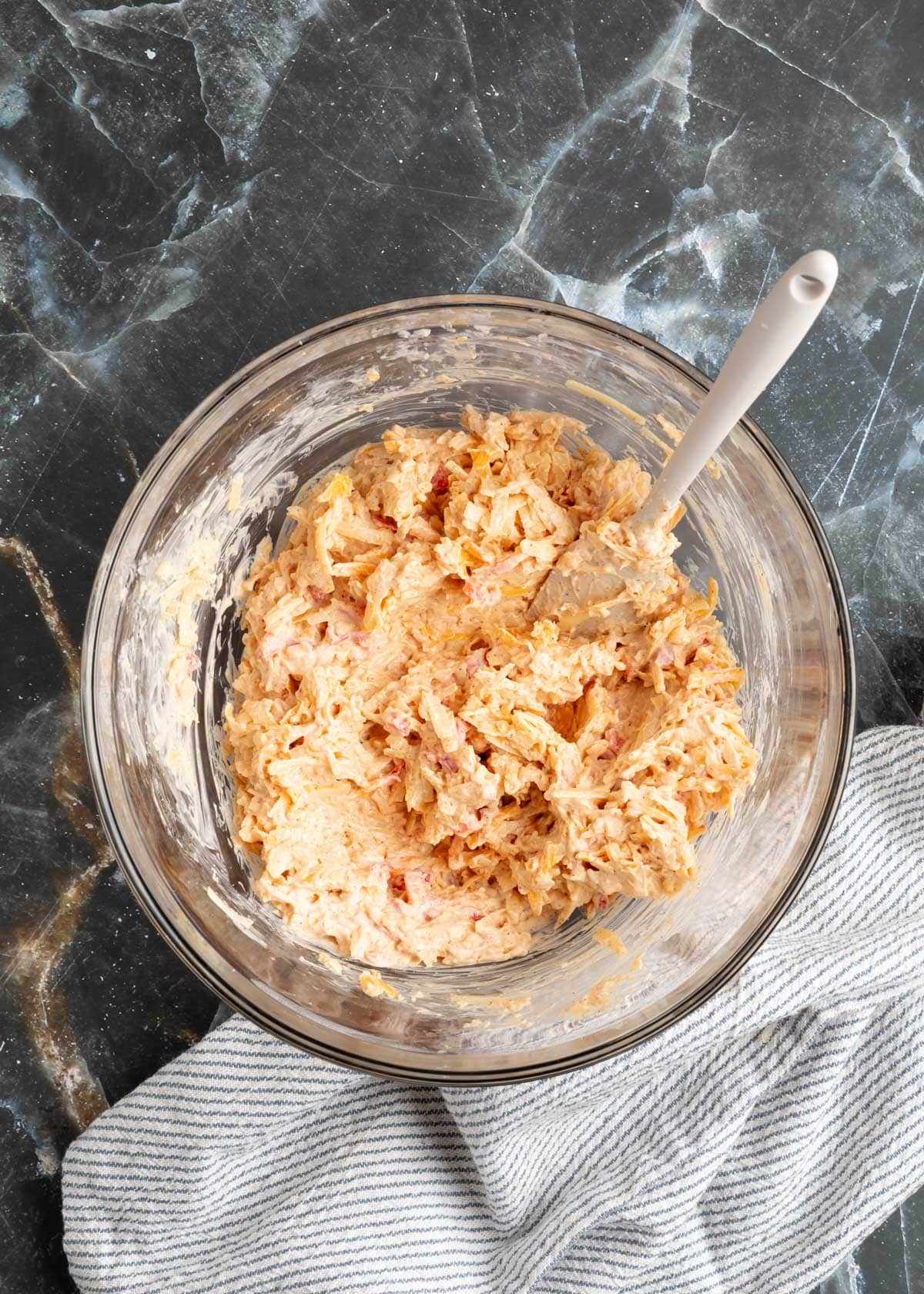 mixed smoky bacon pimento cheese in a glass bowl with a rubber spatula