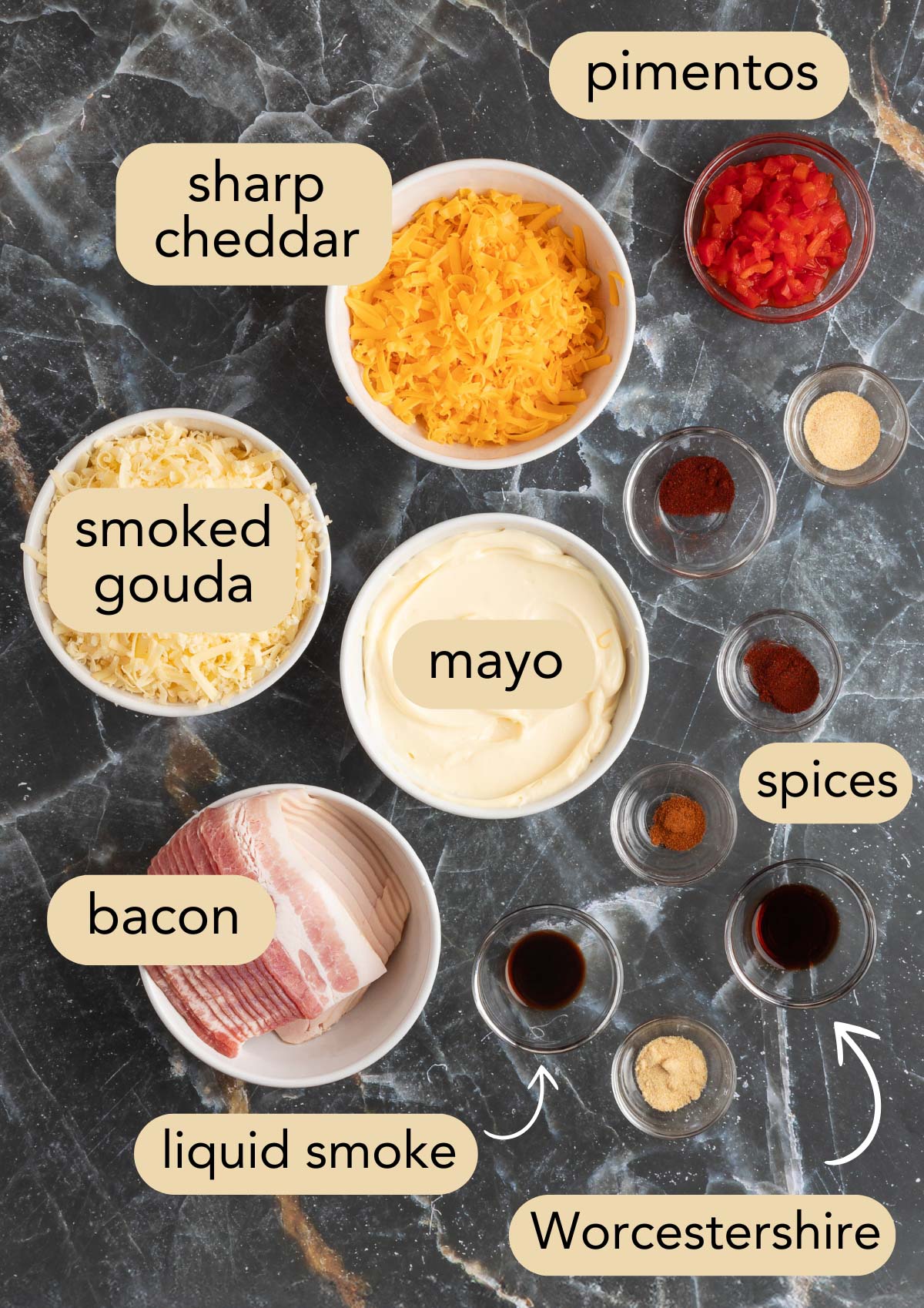 overhead of ingredients needed to make bacon pimento cheese in bowls on a black marble surface with text label overlays