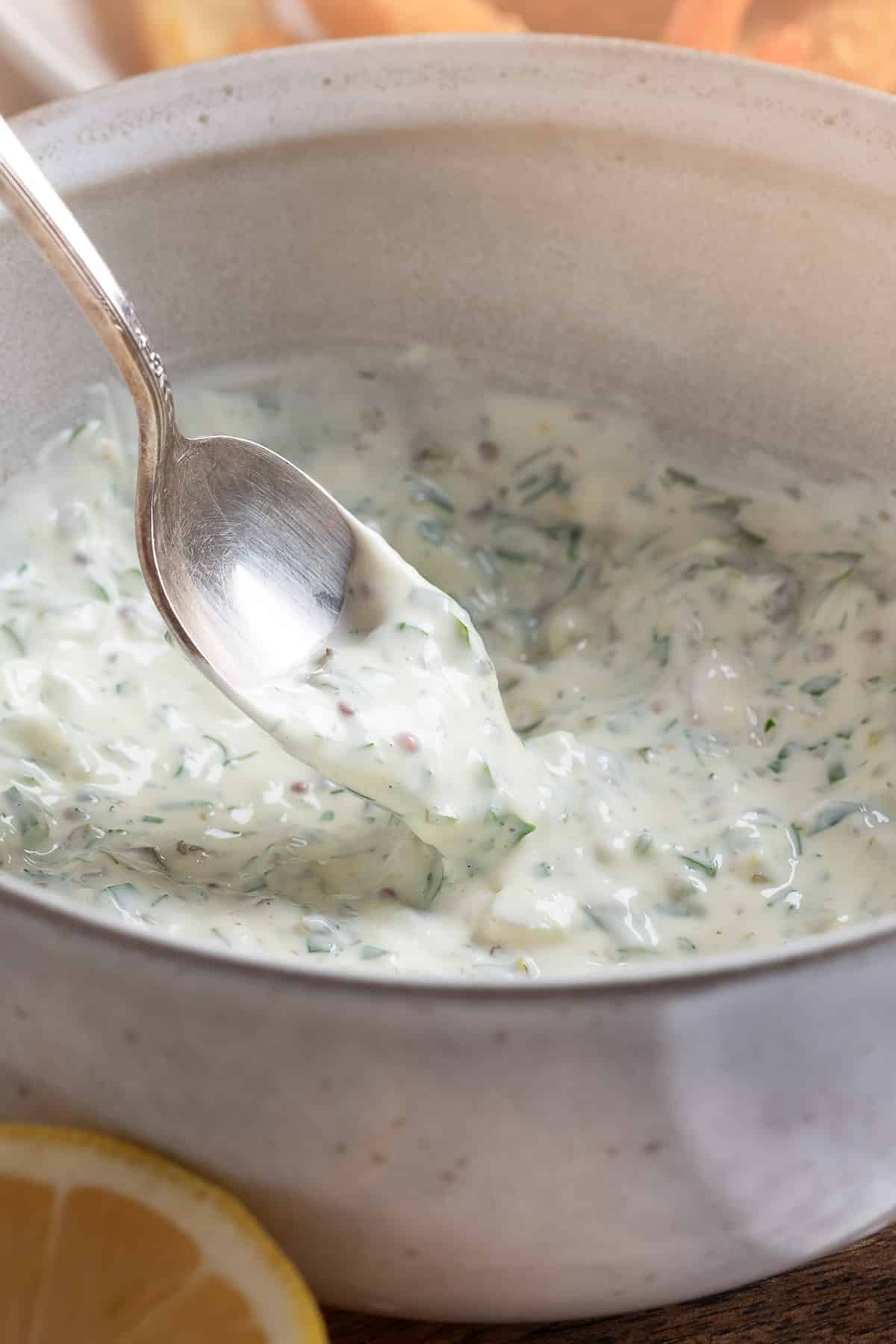 Tangy Tartar Sauce being scooped from a mixing bowl with a silver spoon